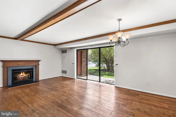 a view of an empty room with wooden floor fireplace and a window