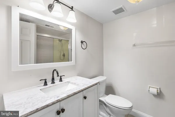 a bathroom with a granite countertop sink a toilet and a mirror