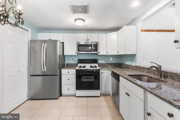 a kitchen with granite countertop a refrigerator and a sink