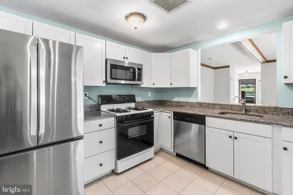 a kitchen with granite countertop white cabinets and stainless steel appliances