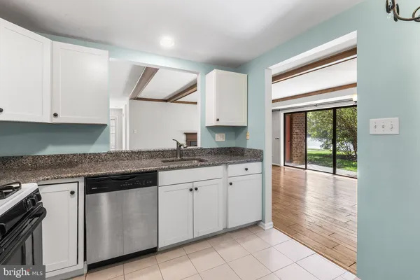 a kitchen with granite countertop white cabinets stainless steel appliances a sink and a window