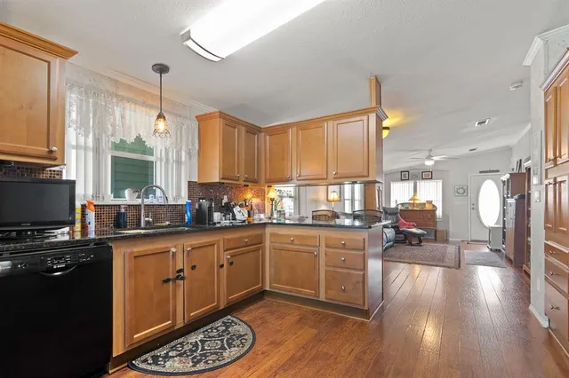 a kitchen with stainless steel appliances a stove top oven a sink a dining table and chairs with wooden floor