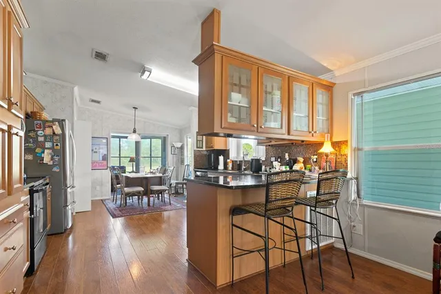 a kitchen with stainless steel appliances granite countertop dining table chairs cabinets and a window