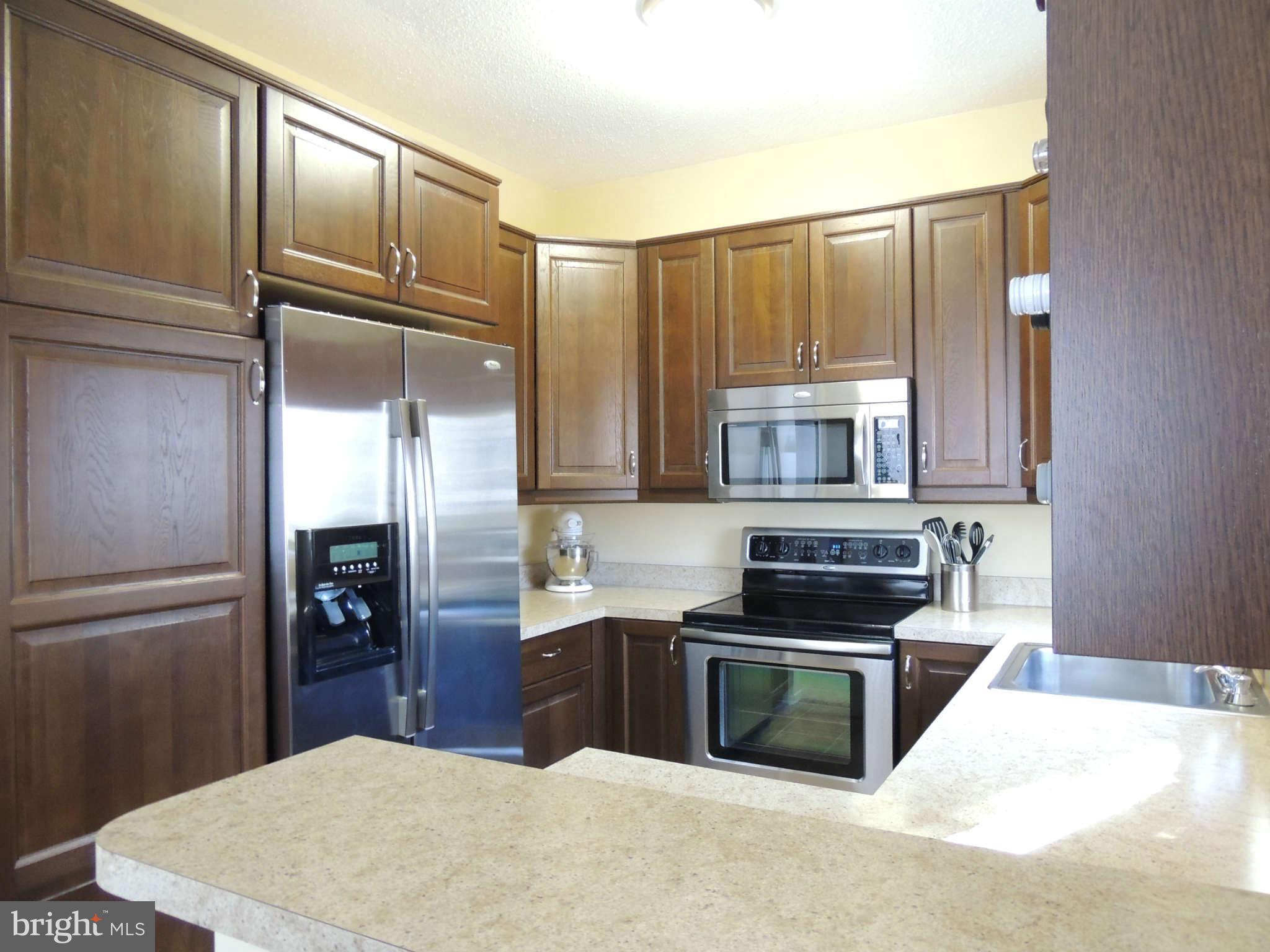11033 Villaridge Court, Unit B Reston, VA 20191 - Photo 7 of 25 a kitchen with kitchen island granite countertop a refrigerator stove and sink