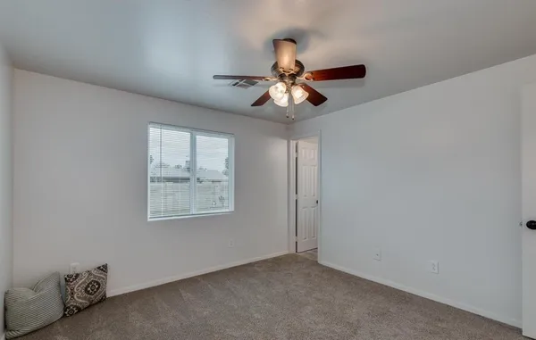 an empty room with windows and fan