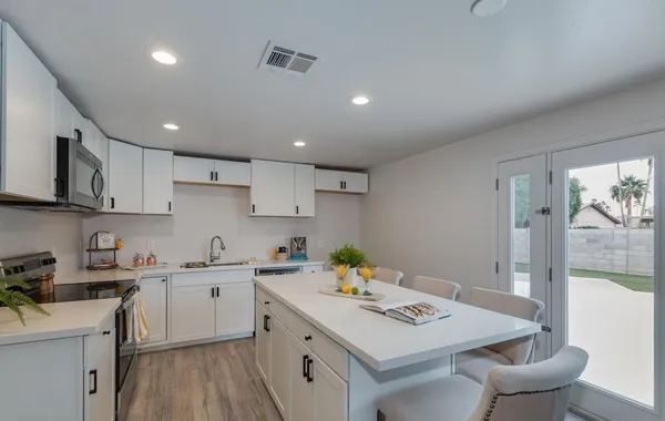 a kitchen that has a lot of cabinets a sink and wooden floor