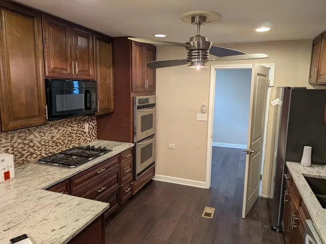 a kitchen with stainless steel appliances granite countertop a refrigerator and a stove top oven