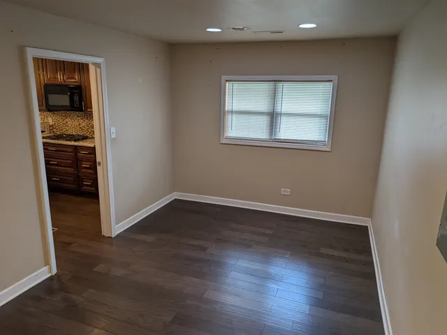 an empty room with wooden floor closet and windows
