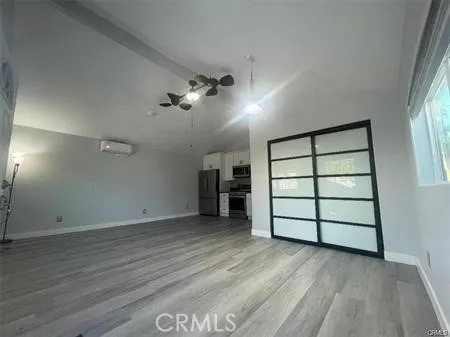 an empty room with wooden floor closet and windows