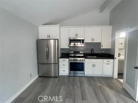a kitchen with granite countertop a refrigerator and a stove top oven
