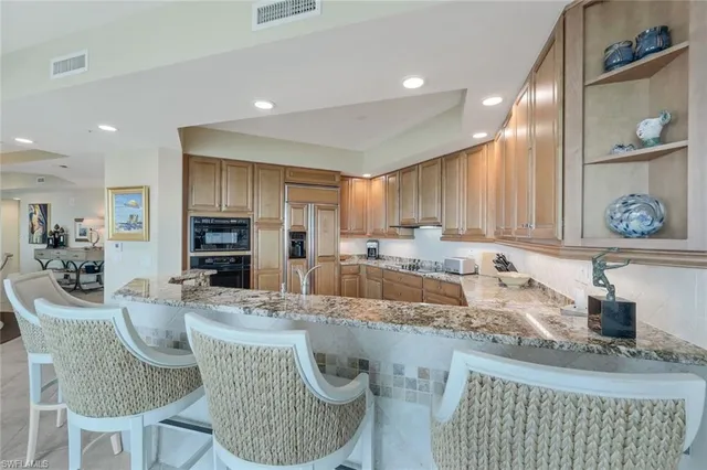 a kitchen with granite countertop a sink a stove a dining table and chairs