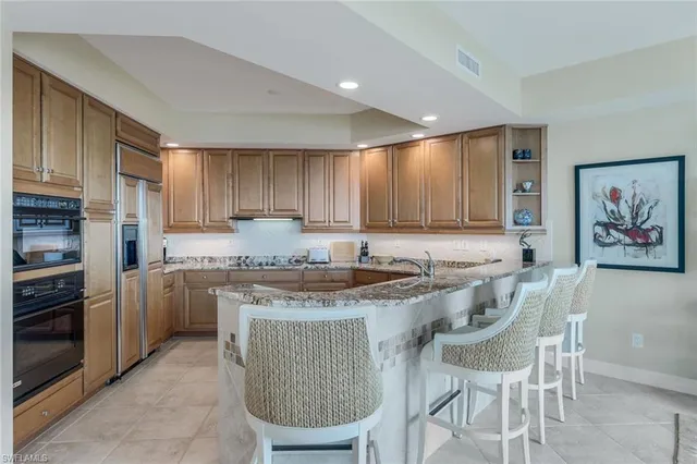 a kitchen with stainless steel appliances granite countertop a stove a sink a microwave a refrigerator and cabinets