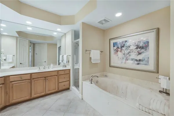 a spacious bathroom with a tub a double vanity sink and a mirror