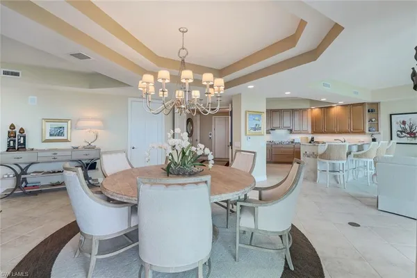 a dining room with furniture a chandelier and kitchen view
