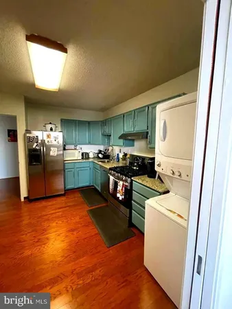 a kitchen with stainless steel appliances granite countertop a refrigerator a sink dishwasher a stove and white countertops with wooden floor