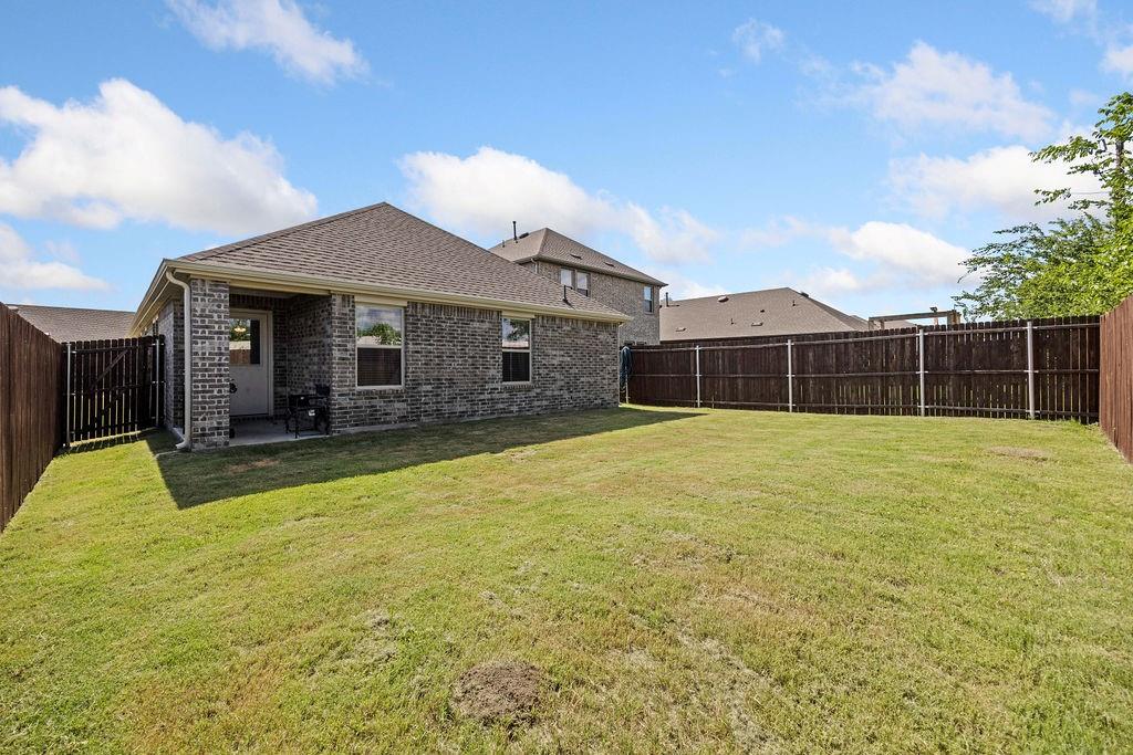 822 Ramble Road Lavon, TX 75166 - Photo 30 of 35 Expansive backyard featuring a manicured lawn, full privacy fencing, and a covered concrete patio