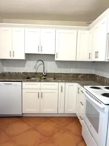 a kitchen with granite countertop white cabinets and white appliances