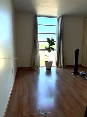 an empty room with wooden floor and a potted plant