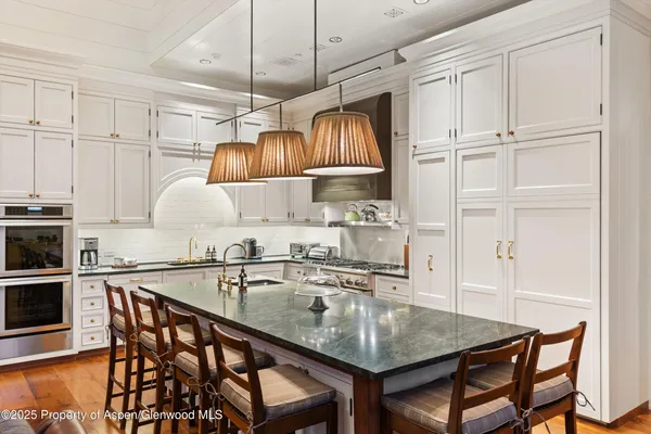 a kitchen with stainless steel appliances granite countertop a table chairs and a wooden floor