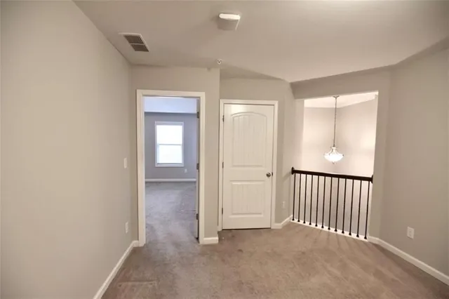 a view of a hallway with wooden floor and a bathroom