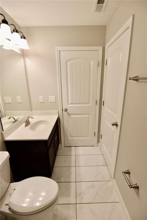 1223 Foxcroft Lane Cumming, GA 30041 - Photo 27 of 33 a bathroom with a sink a toilet a mirror and vanity