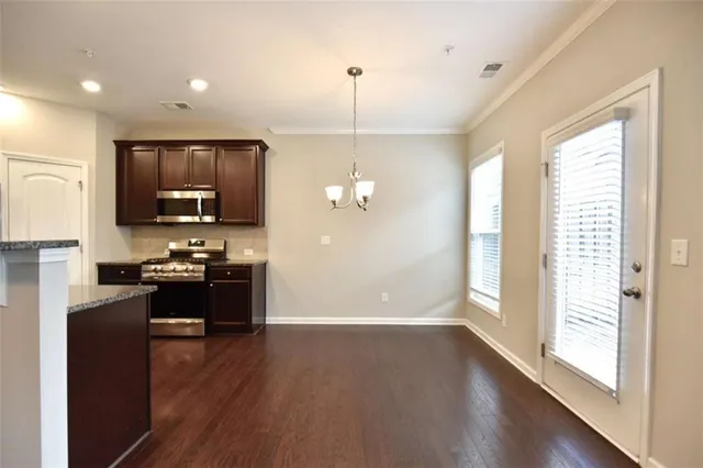 a kitchen with refrigerator a stove and a wooden floor