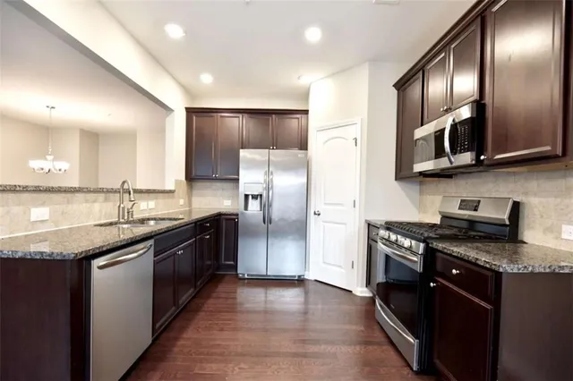 a modern kitchen with stainless steel appliances granite countertop a stove a sink and a refrigerator