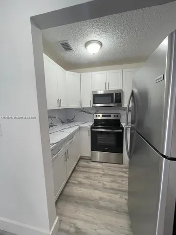 a kitchen with a refrigerator sink and cabinets