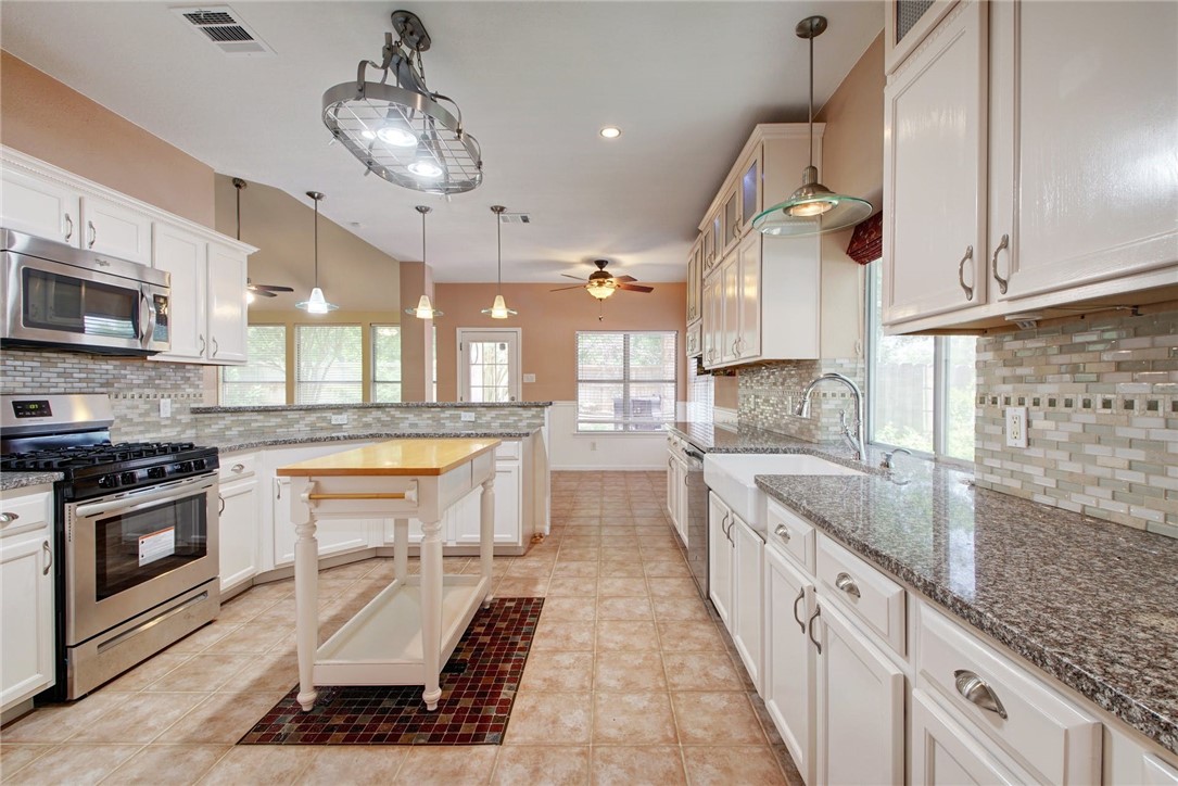 a large kitchen with stainless steel appliances granite countertop a lot of counter space a sink and a stove
