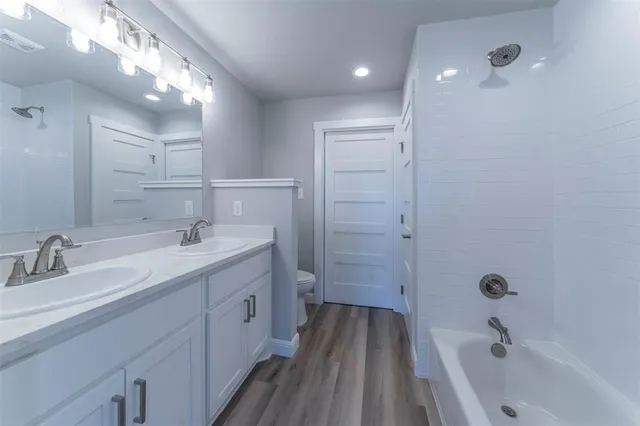 a bathroom with a double vanity sink a mirror and a bathtub