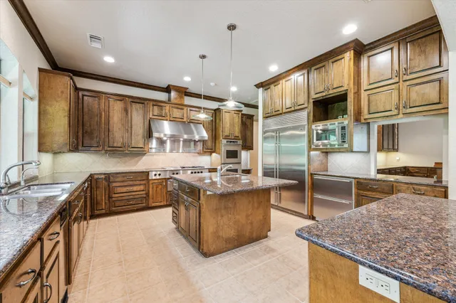 a kitchen with stainless steel appliances granite countertop a stove top oven a sink a counter space and living room view