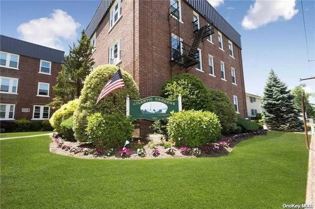 a front view of a multi story residential apartment building with yard and green space