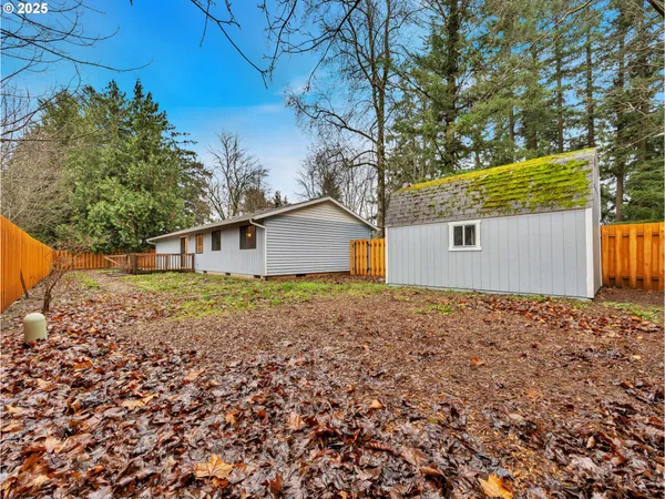 a backyard of a house with large trees and wooden fence