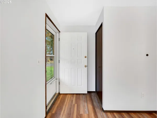 a view of a hallway with wooden floor and a bathroom
