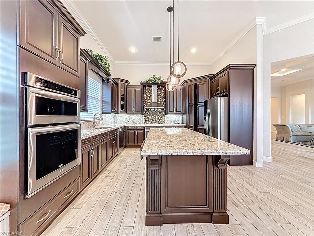 5550 Ferrari Avenue Ave Maria, FL 34142 - Photo 22 of 50 a kitchen with stainless steel appliances granite countertop a kitchen island a stove a refrigerator a oven and a cabinets with wooden floor