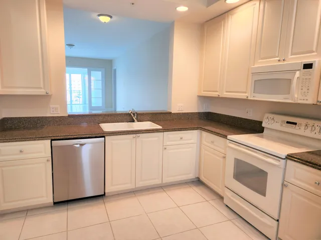 a kitchen with granite countertop white cabinets and white appliances