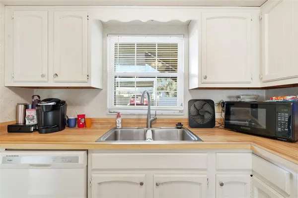 a kitchen with stainless steel appliances granite countertop white cabinets and a window