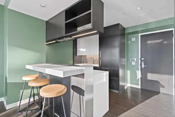 a living room with stainless steel appliances kitchen island granite countertop a sink and a stove with wooden floor