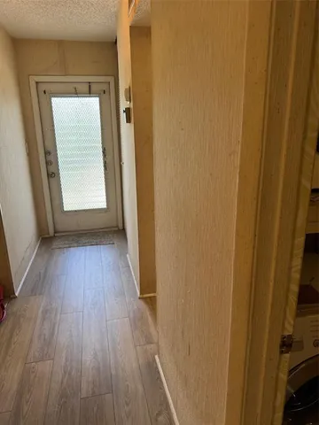 a view of a hallway with wooden floor and a window
