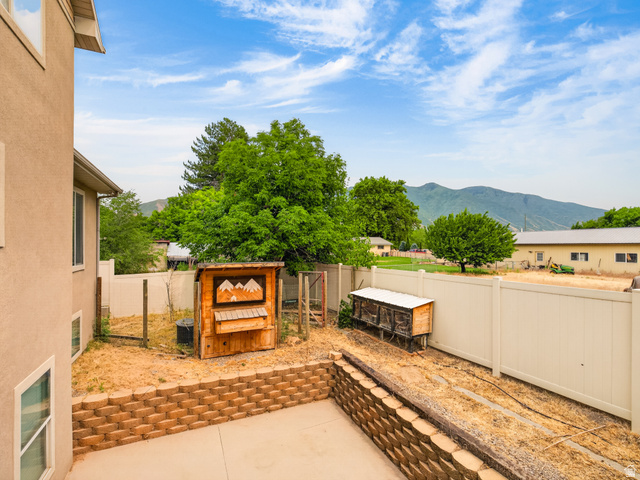 1279 West 1500th Street North Mapleton, UT 84664 - Photo 69 of 83 Expansive backyard featuring a concrete patio, tiered retaining wall, and durable vinyl fencing