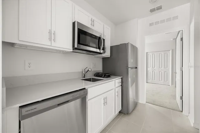 a kitchen with stainless steel appliances white cabinets and a refrigerator