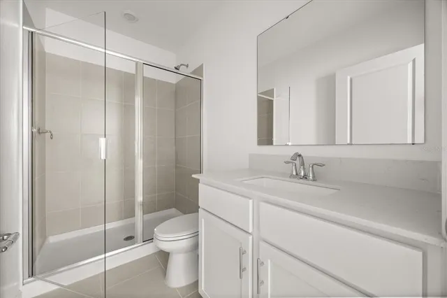 a bathroom with a shower sink vanity mirror and toilet