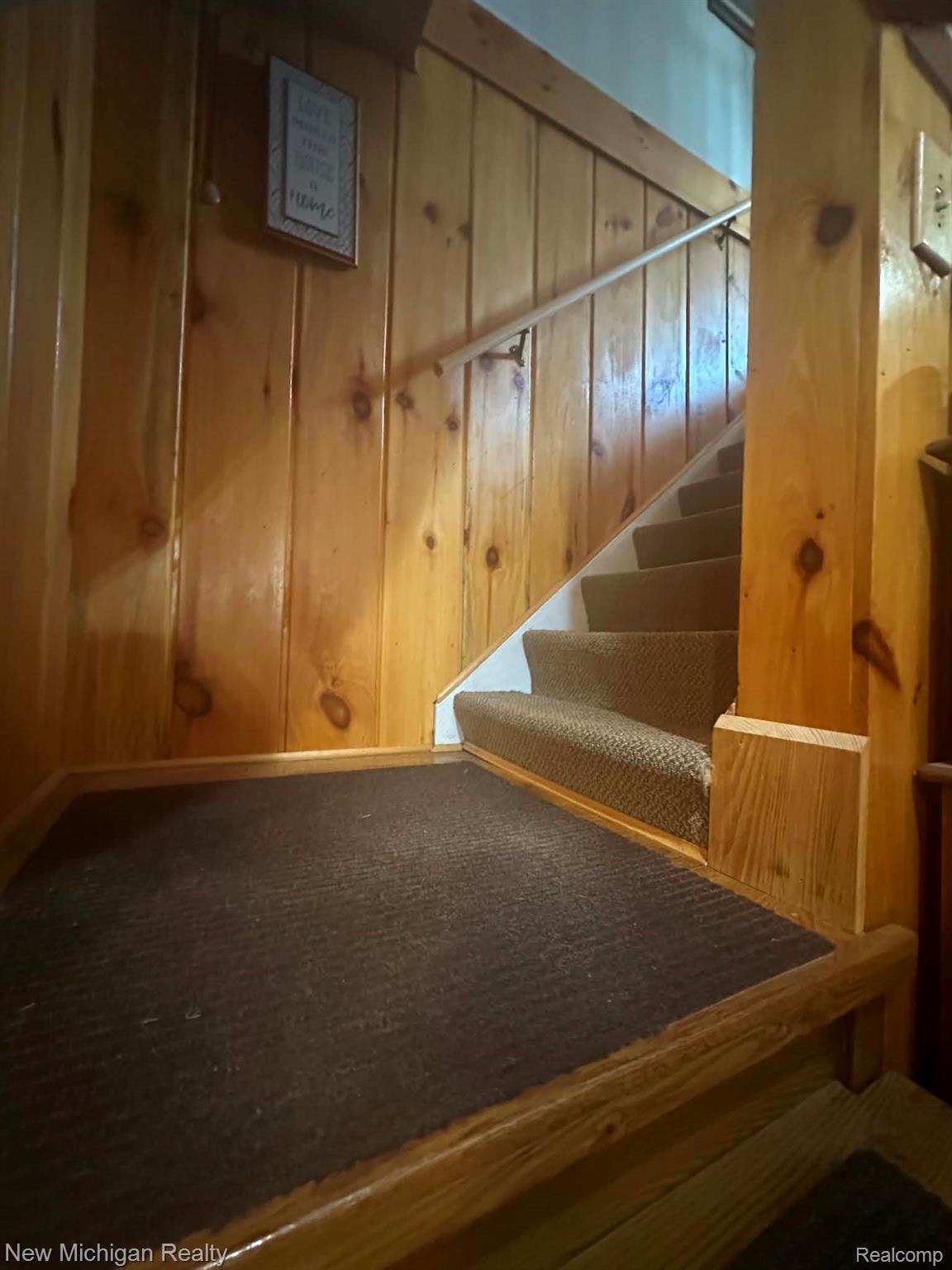7415 Farrand Road Clio, MI 48420 - Photo 26 of 31 Staircase featuring wood paneling, wood handrail, and carpeted treads