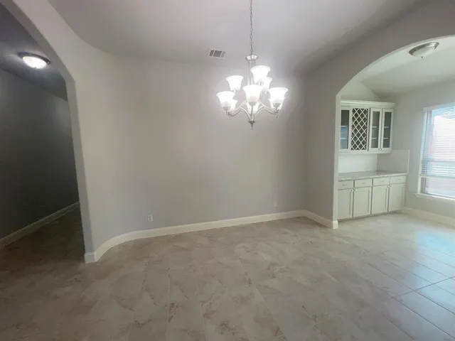 an empty room with chandelier and windows