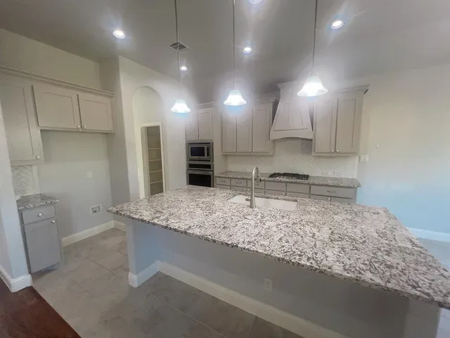 a kitchen with kitchen island sink stove and refrigerator