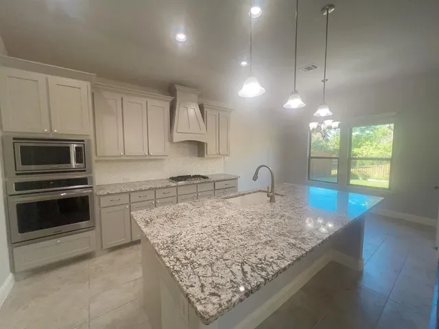 a kitchen with stainless steel appliances granite countertop a sink stove and microwave