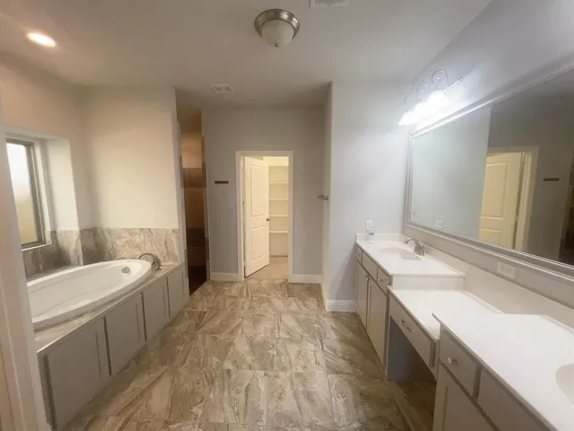 a spacious bathroom with a double vanity sink a mirror and a bathtub