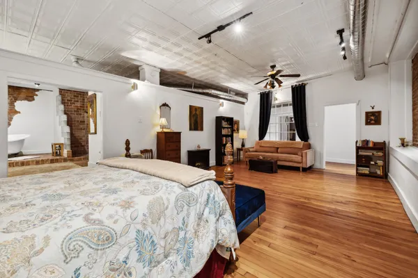 a large bedroom with wooden floor and furniture