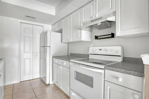 a kitchen with granite countertop white cabinets and white appliances
