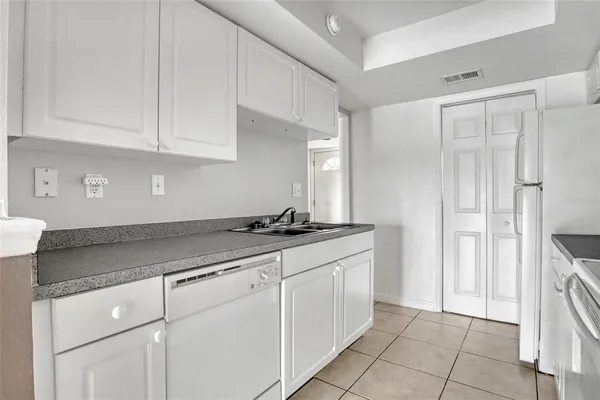 a kitchen with granite countertop white cabinets and white appliances